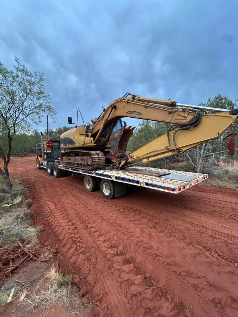 Heavy excavator hauled on a flatbed truck by D&O Crane in Northern Arizona.